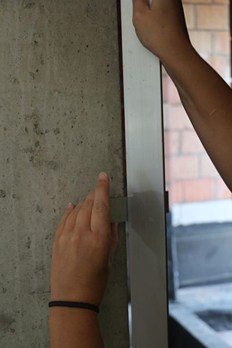 Mesure de la rectitude des bords d’un mur en béton à l’aide d'une latte rigide de 2 m et d’un calibre d’épaisseur.